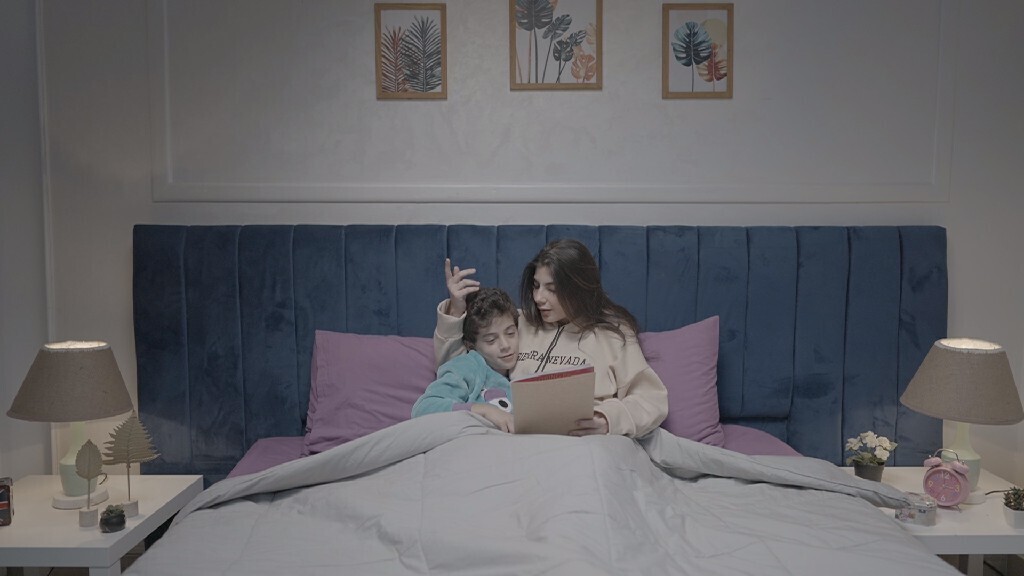 a woman reading a story to her son in bed