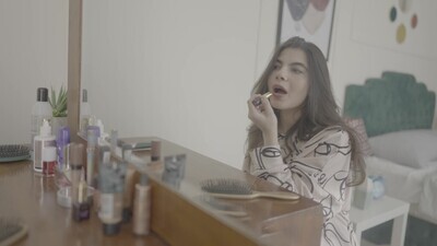 امراة تجلس امام المرأة تضع احمر شفاه 