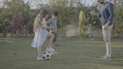 a father playing football with his children in the garden