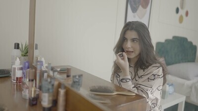 امراة تجلس امام المرأة تضع احمر شفاه 