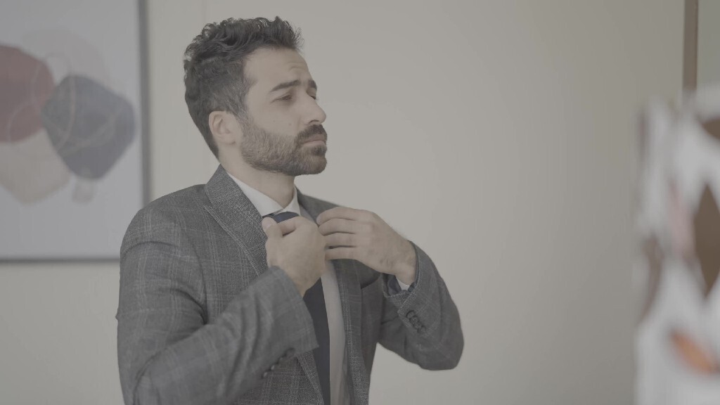 رجل يقف امام المرأة يرتدى سترة 