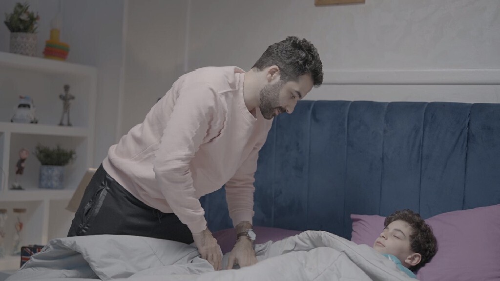 a father carrying his boy and putting him in bed