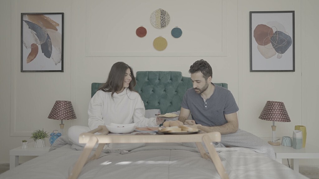 a man and a woman having breakfast on the bed
