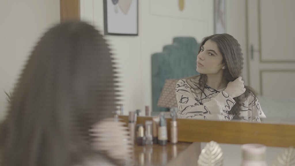 a woman sitting in front of the mirror brushing her hair