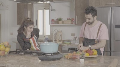 a man and a woman standing and cooking in the kitchen