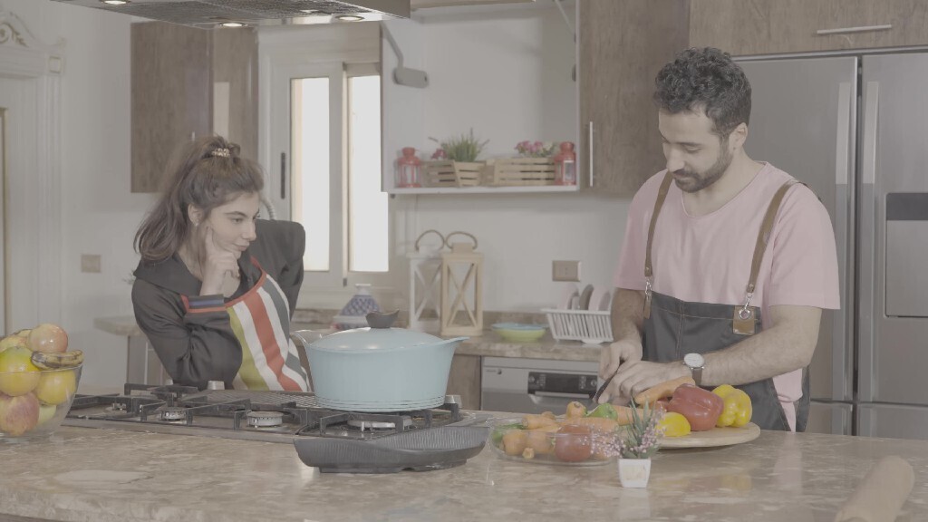 a man and a woman standing and cooking in the kitchen