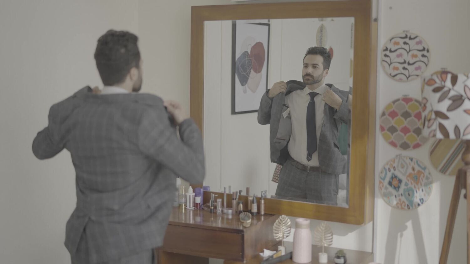 رجل يقف امام المرأة يرتدى سترة 