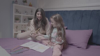 a mother with her daughter drawing together on the bed
