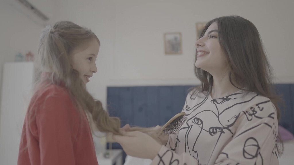 a mother brushes her daughter&#39;s hair