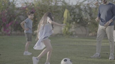اب يلعب كرة قدم مع اطفاله فى الحديقة 