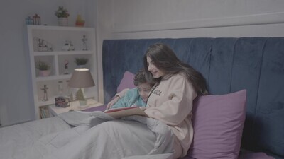 a woman reading a story to her son in bed