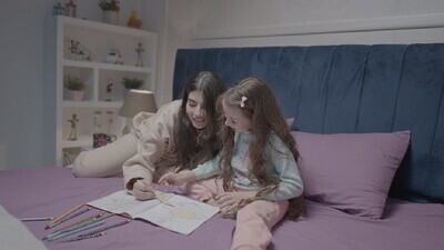 a mother with her daughter drawing together on the bed