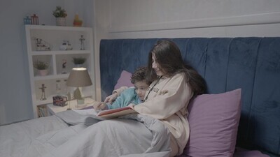 a woman reading a story to her son in bed