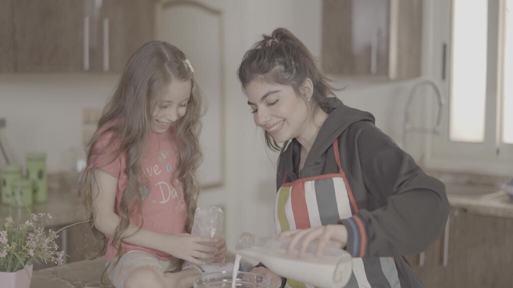 a girl helping her mom in the kitchen