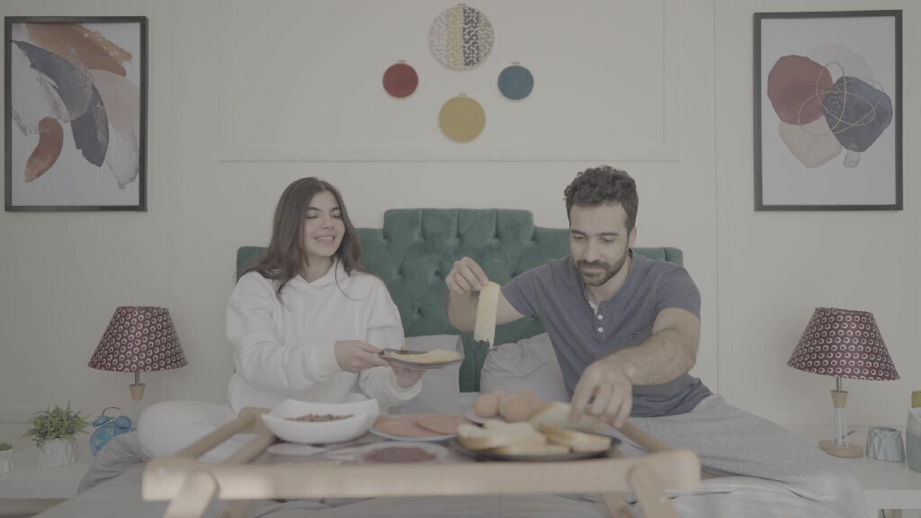 a man and a woman having breakfast on the bed