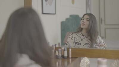 a woman sitting in front of the mirror brushing her hair