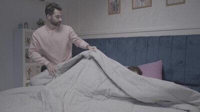 a father carrying his boy and putting him in bed
