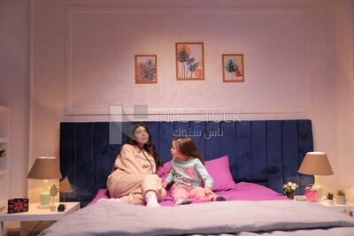 a mother sitting with her daughter and talking in the bed