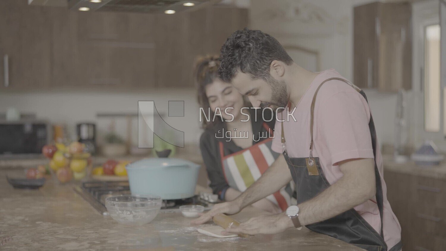 a man and a woman standing and cooking in the kitchen