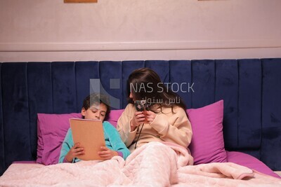 a mother sitting on the phone while her son studies