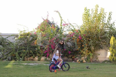 a woman helping her daughter ride a bike