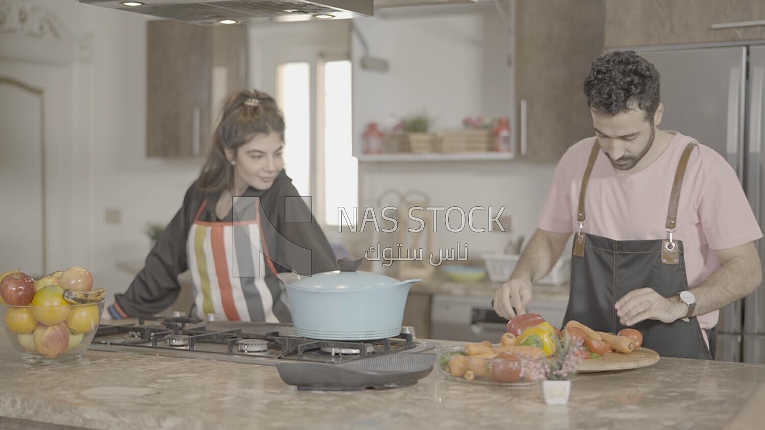 a man and a woman standing and cooking in the kitchen