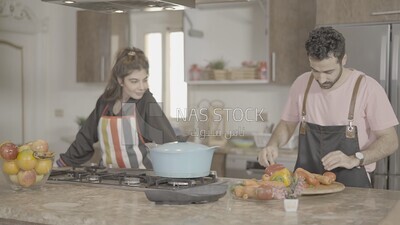 a man and a woman standing and cooking in the kitchen