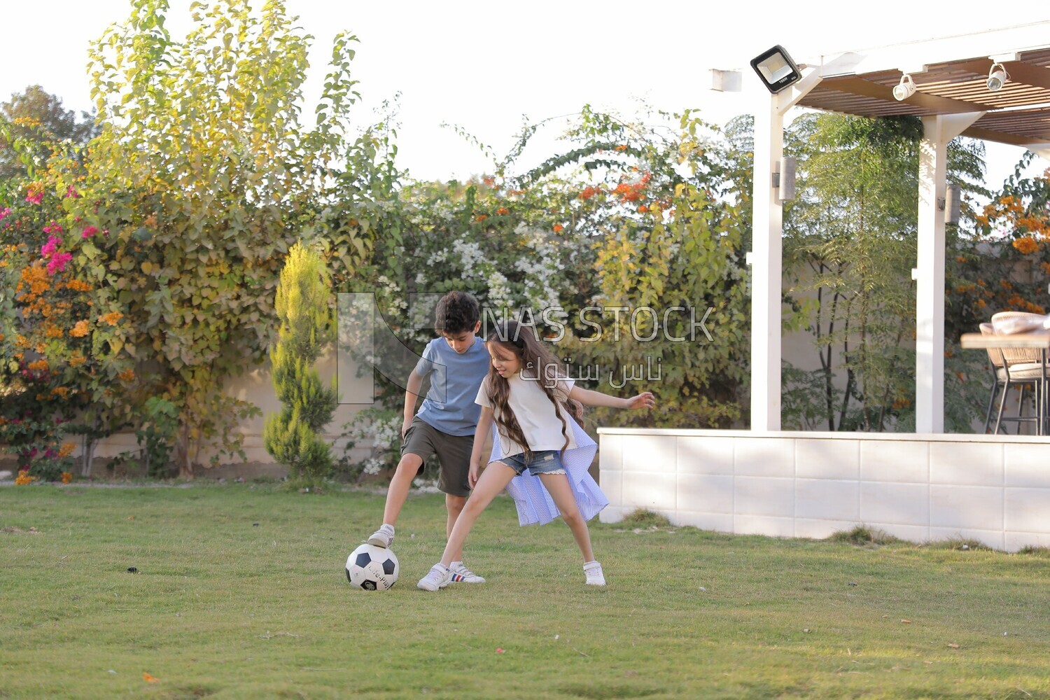 a brother playing football with his sister in the garden