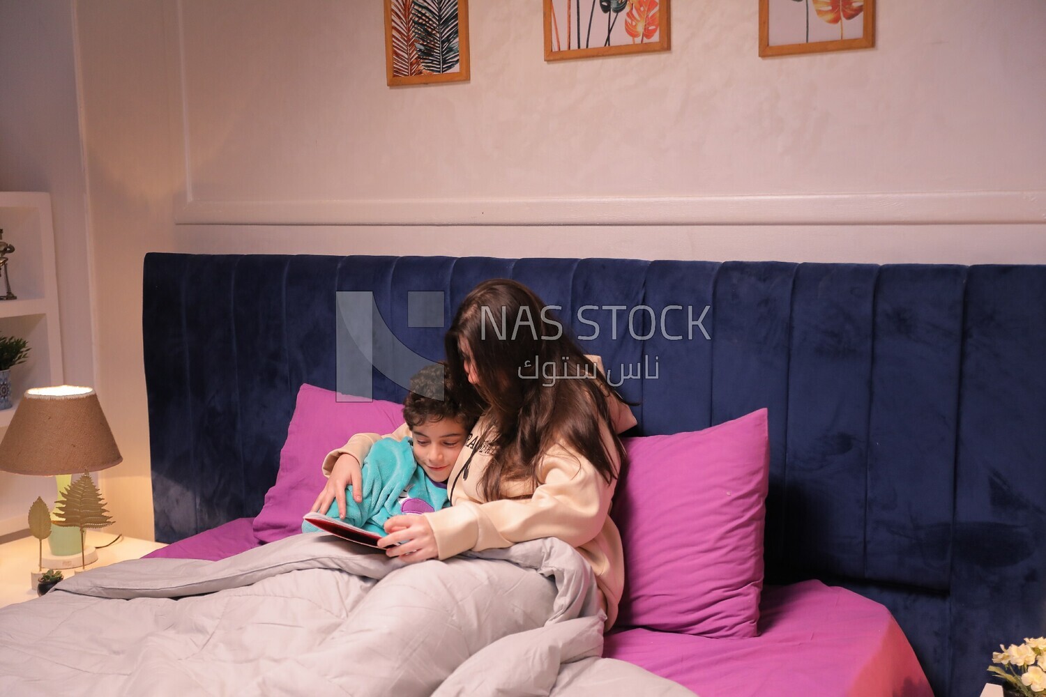 a woman reading a story to her son in bed