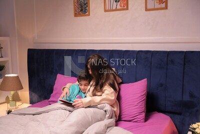 a woman reading a story to her son in bed