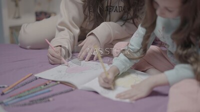 a mother with her daughter drawing together on the bed