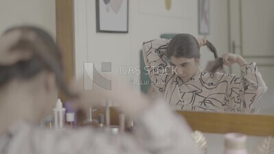 a woman sitting in front of the mirror brushing her hair