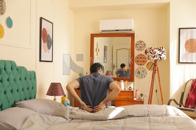 a man  sitting in bed waking up looks tired