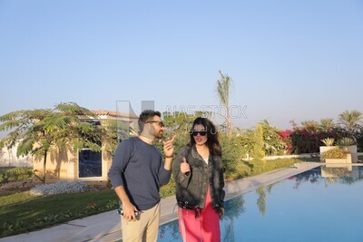 a husband with his wife standing in front of a swimming pool