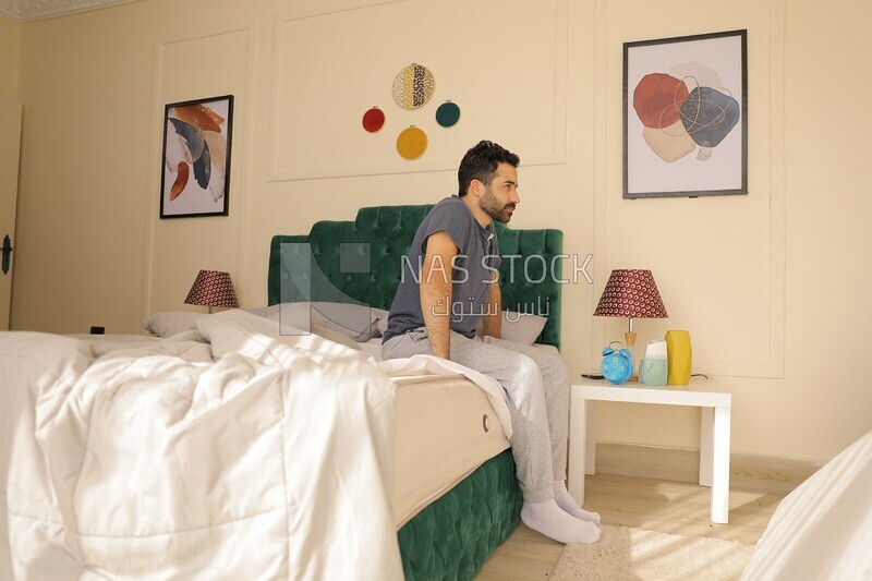 a man sitting in bed waking up looks tired