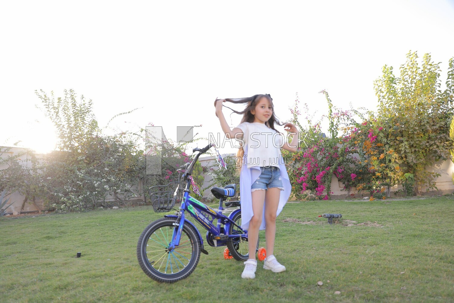 a girl standing beside a bike in the garden