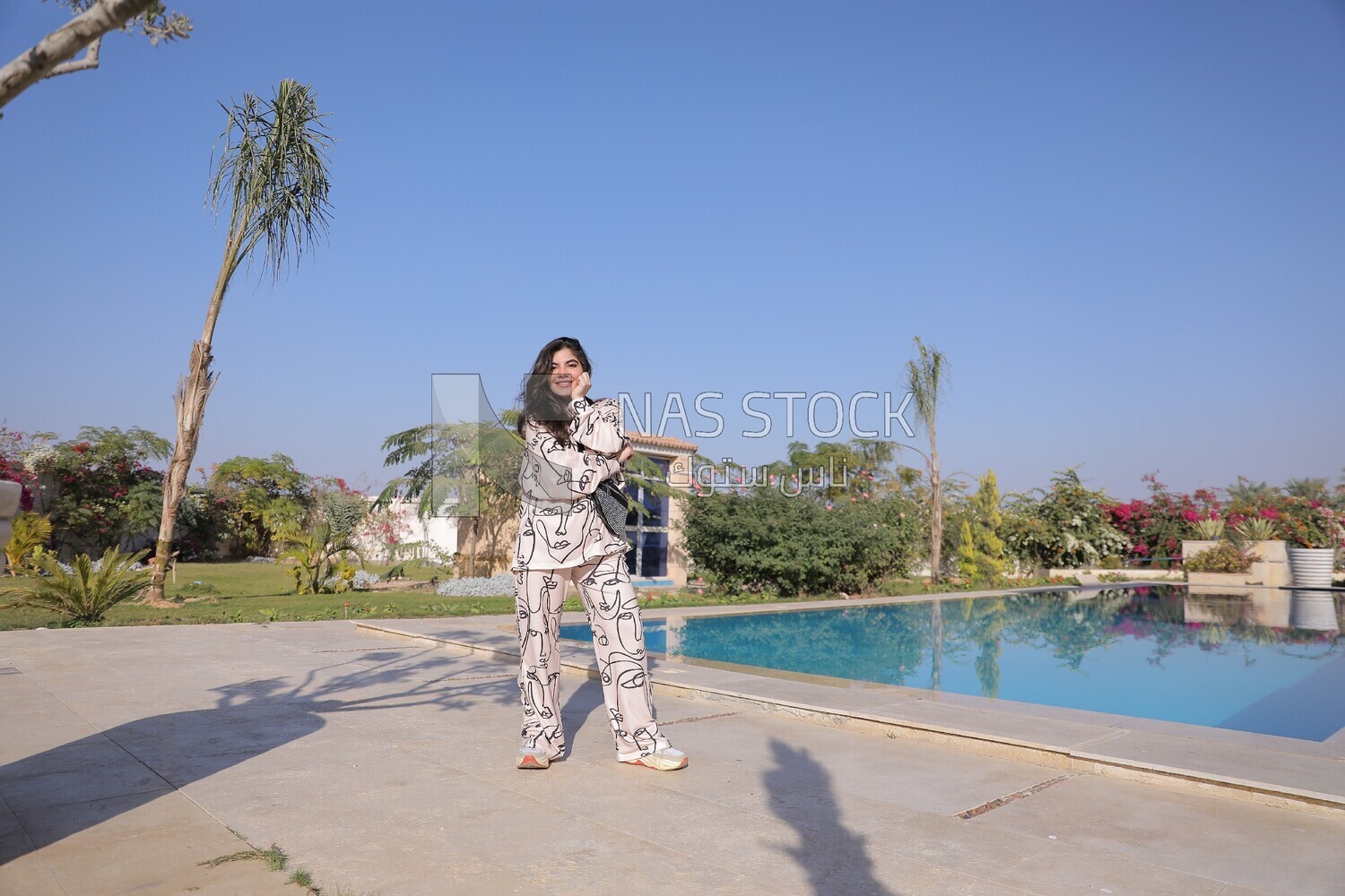a woman standing in the garden beside a swimming pool
