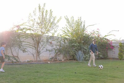 a father playing football with his son in the garden