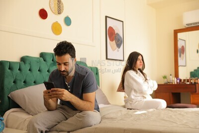 a man texting on the phone while her wife is beside him