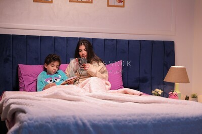 a mother sitting on the phone while her son studies