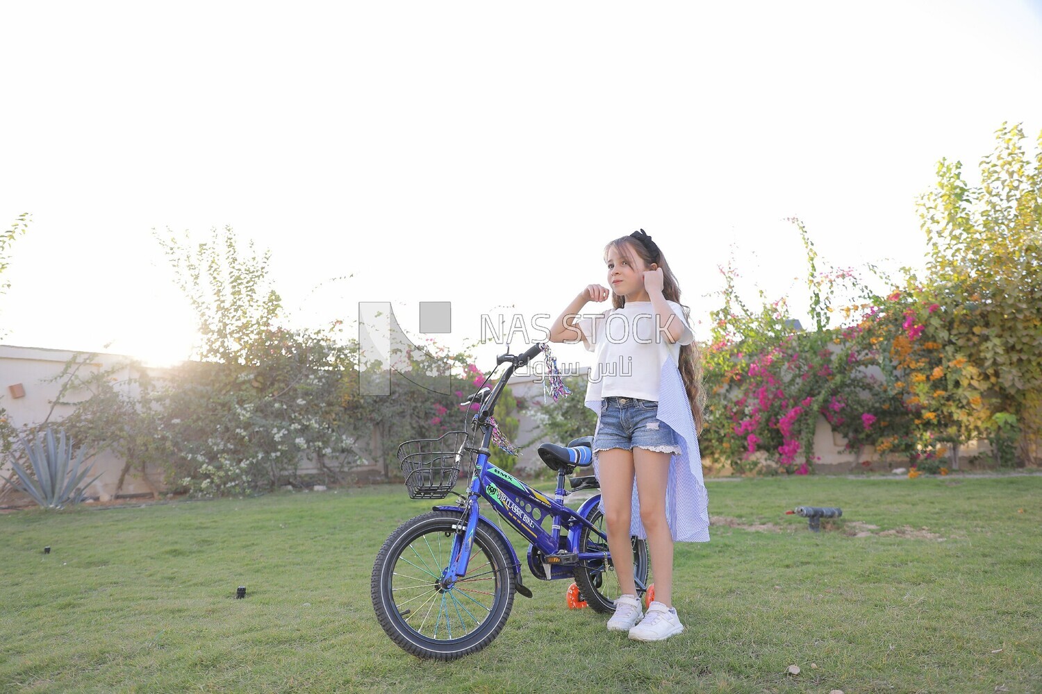 a girl standing beside a bike in the garden