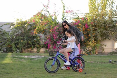 a woman helping her daughter ride a bike