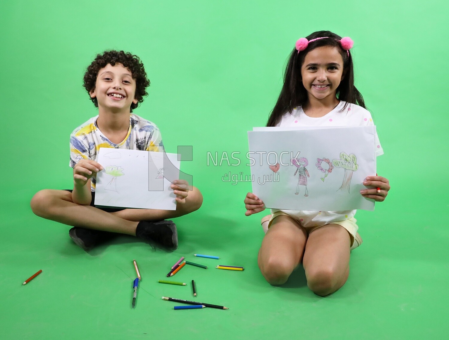 A boy and a girl sitting on the floor and drawing