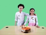 boy and a girl standing in front of a table