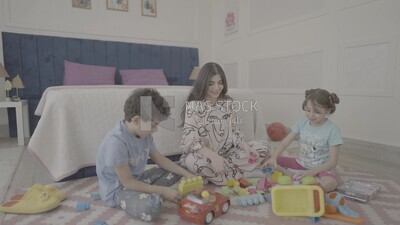 امراة تجلس مع اطفالها يلعبون 