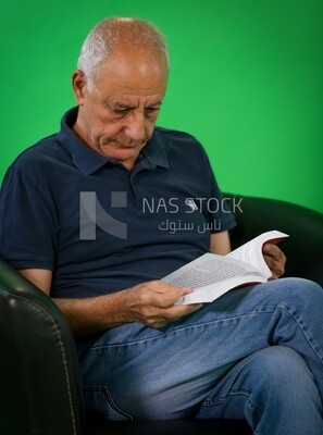 An elderly man sitting and reading a book