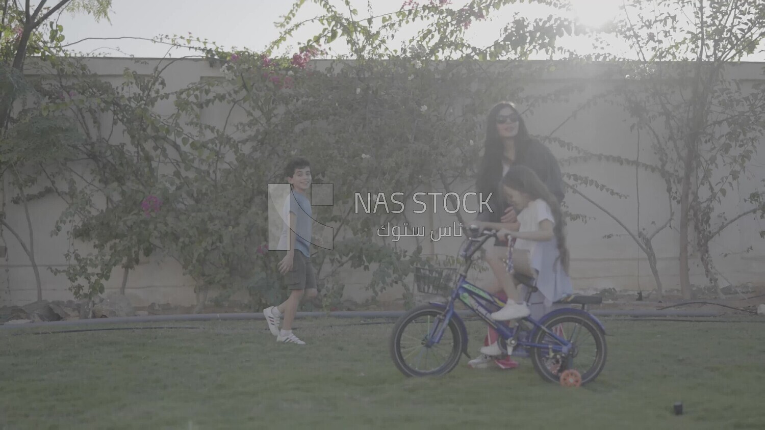 a woman helping her daughter ride a bike