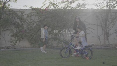 a woman helping her daughter ride a bike