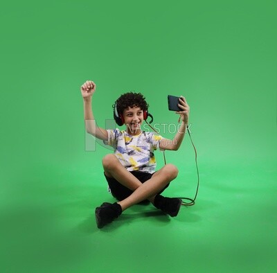 A boy holding a tablet and wearing a headphone