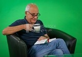 An elderly man sitting and reading a book